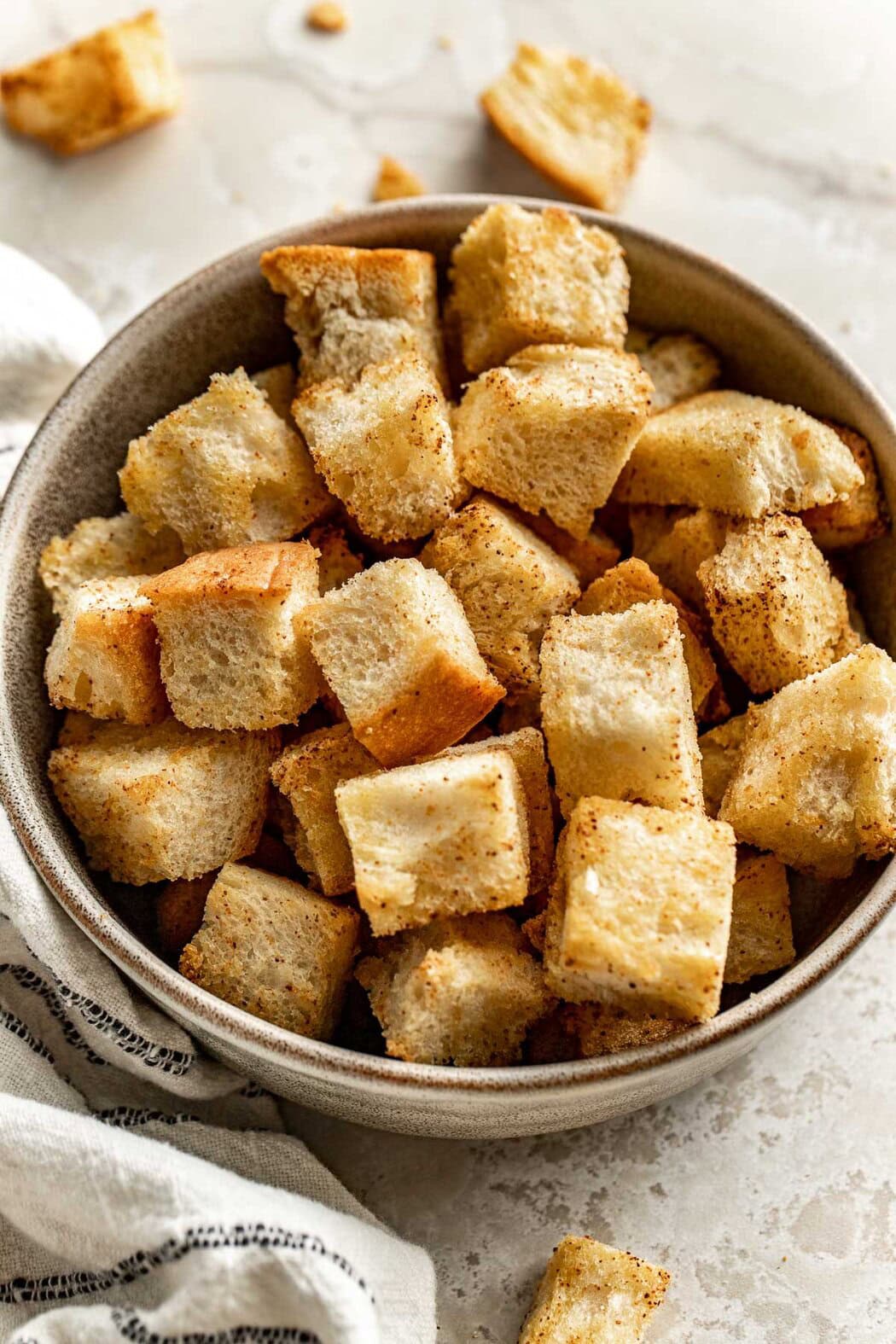 Close up view of a bowl of freshly baked Homemade Croutons topped with seasonings