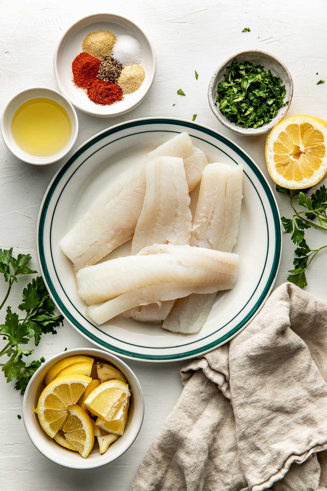 Overhead view of a variety of ingredients for Air Fryer Cod in different sized bowls. 