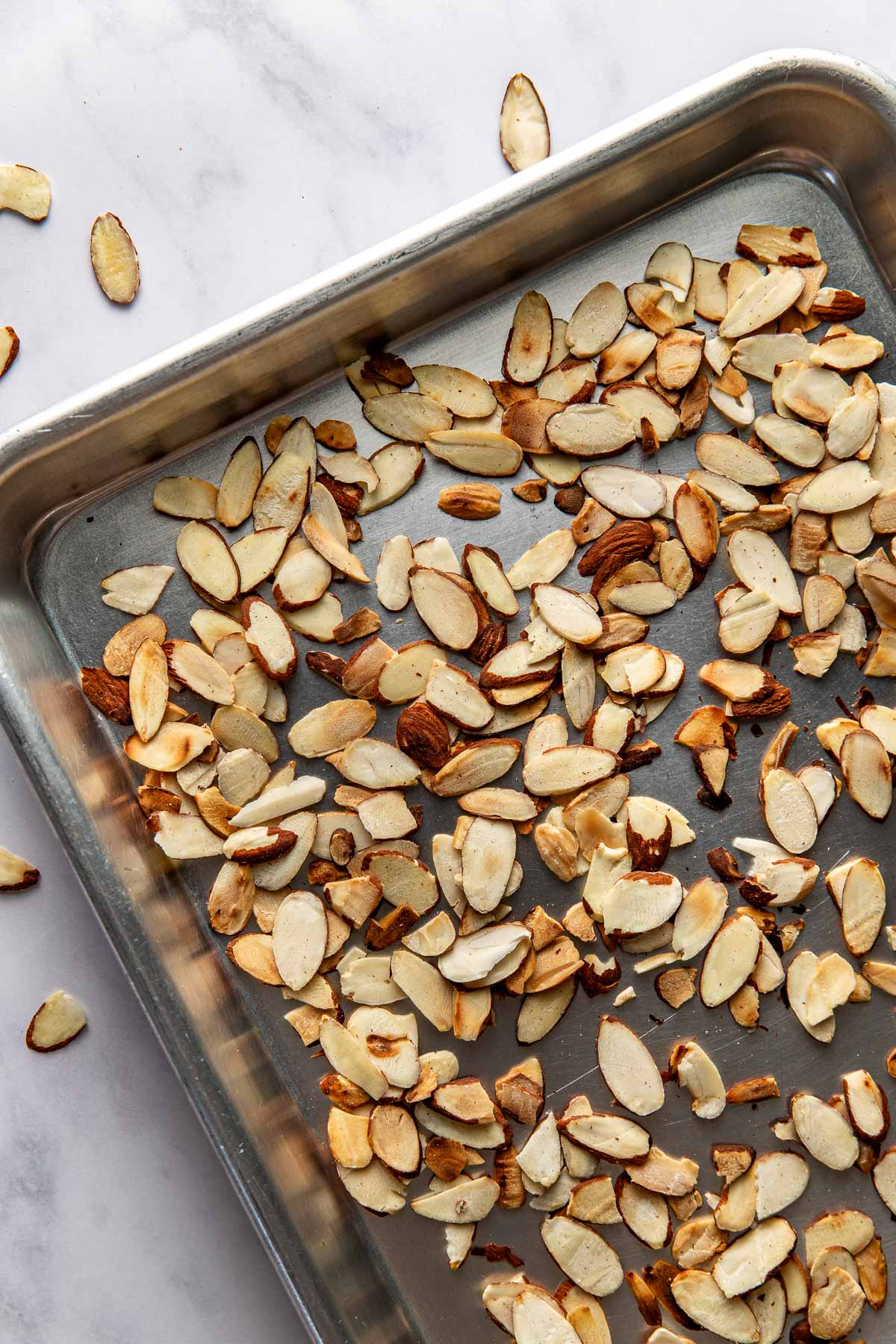 Overhead view of toasted almonds on a sheet pan. 