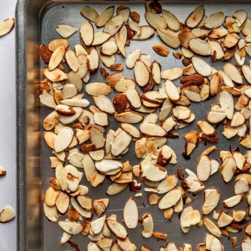 Close up view of a sheet pan of toasted sliced almonds.