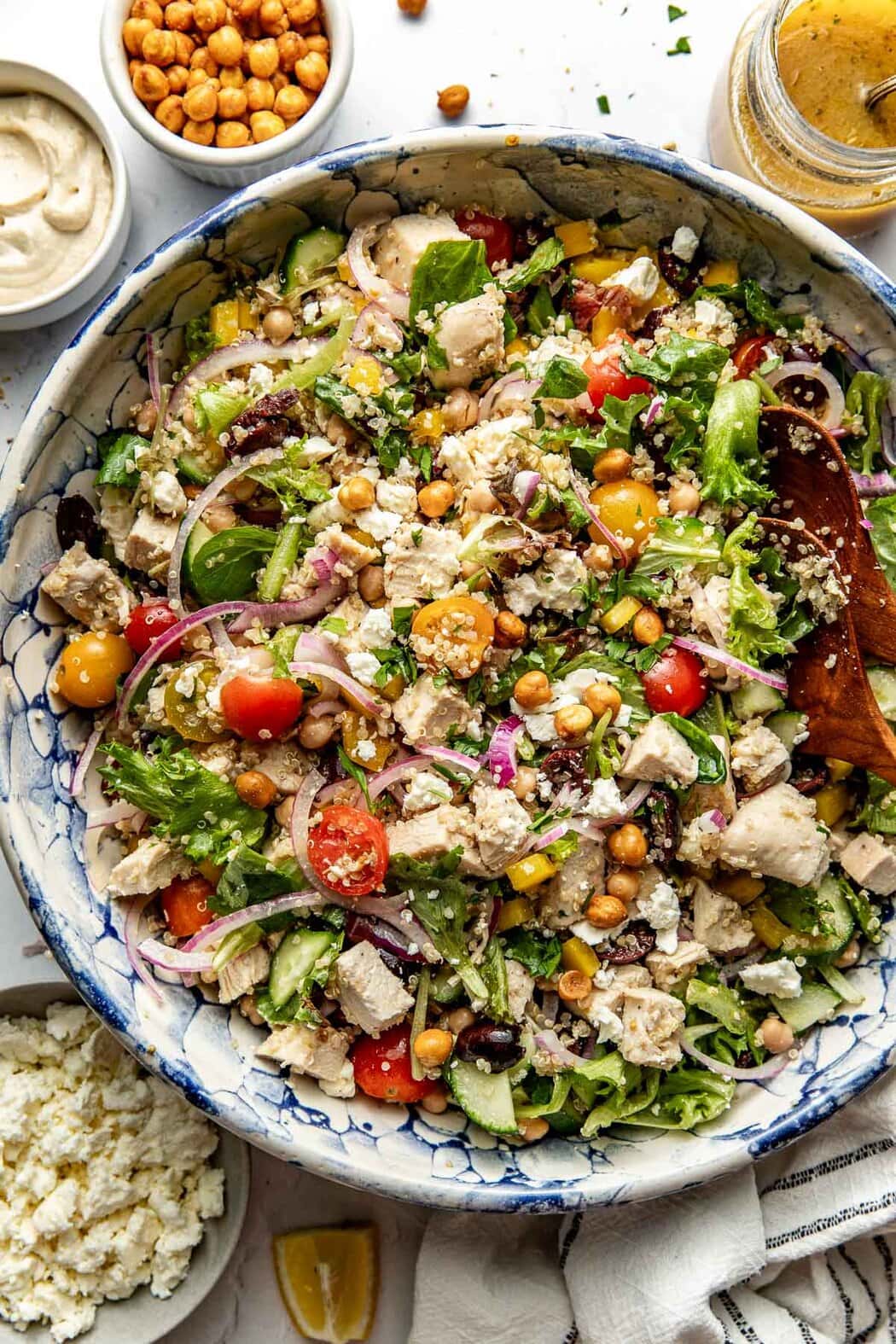 Overhead view of a colorful bowl of Chopped Mediterranean Salad with Chicken topped with fresh herbs and feta cheese.