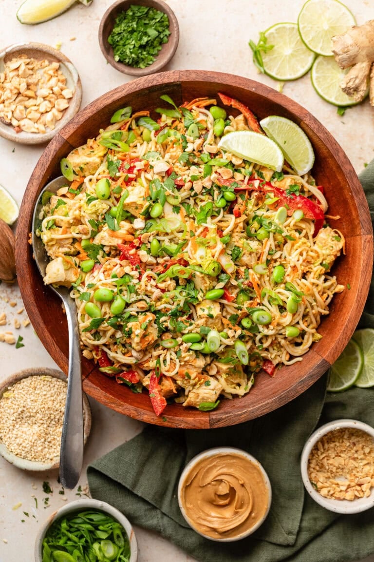 Overhead view of a bowl of Cold Noodle Salad with Peanut Sauce and topped with edamame and garnished with limes. 
