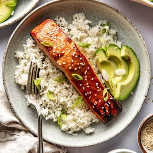 Overhead view of a plate of rice and Miso-Glazed Salmon garnished with avocado slices.