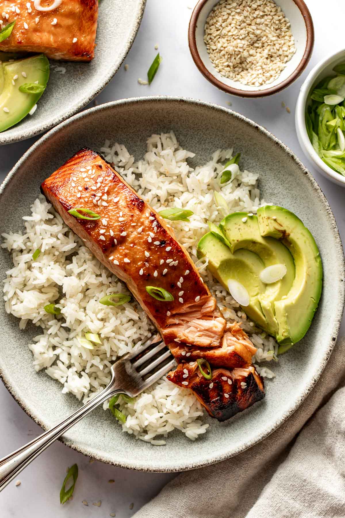 Overhead view of a plate of Miso-Glazed Salmon on top of a bed of white rice and garnished with avocado slices. 