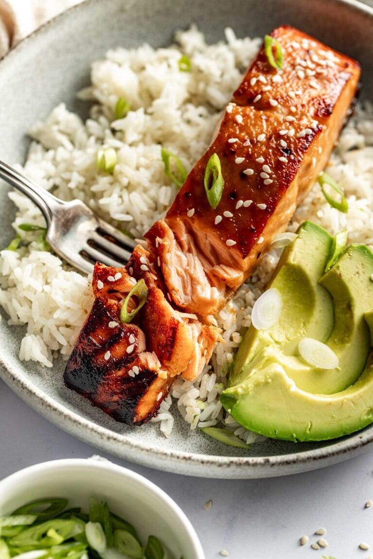 Overhead view of a plate of white rice and a piece of miso glazed salmon with avocado on the side. 