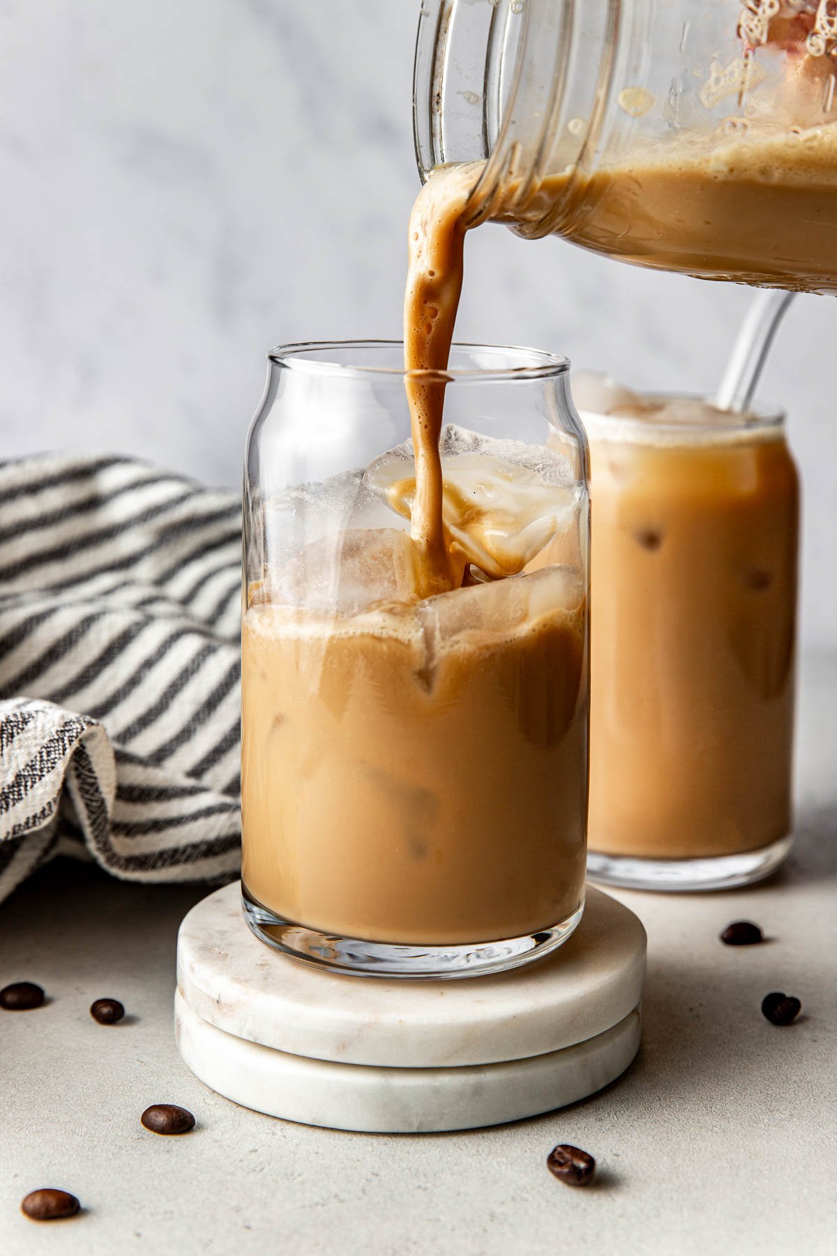 Close up view of a mason jar pouring Protein Coffee into a glass of ice. 