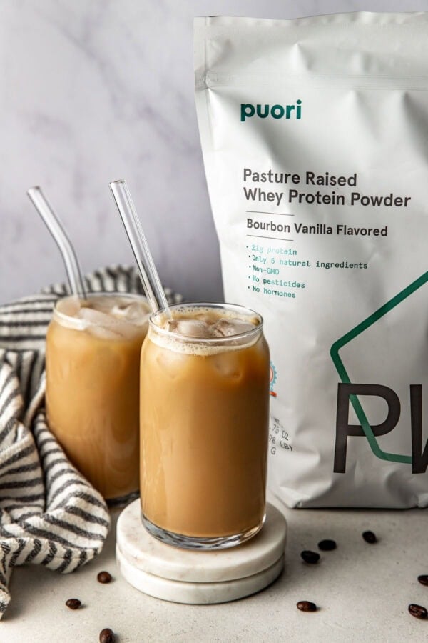 2 glasses of Protein Coffee next to a bag of protein.