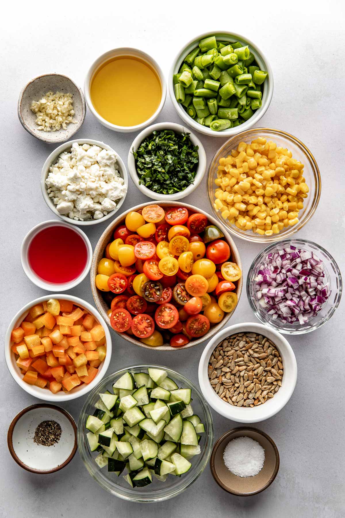 Overhead view of a variety of ingredients for summer salad in different sized bowls. 