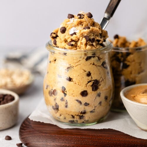 Chickpea cookie dough with mini chocolate chips in a glass jar with a spoon in the dough