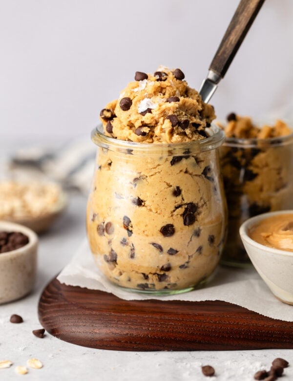 Chickpea cookie dough with mini chocolate chips in a glass jar with a spoon in the dough