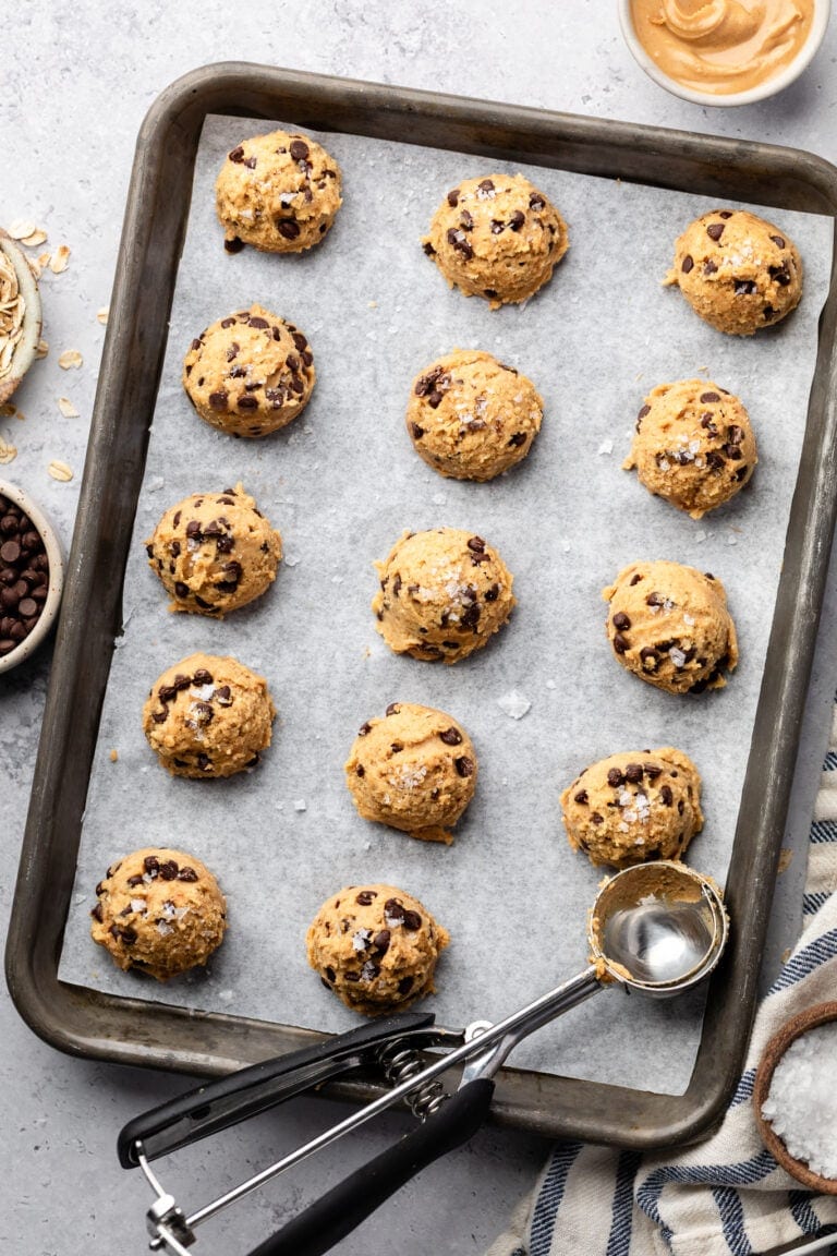 Overhead view of a sheet pan lined with parchment paper topped with cookie dough bites.