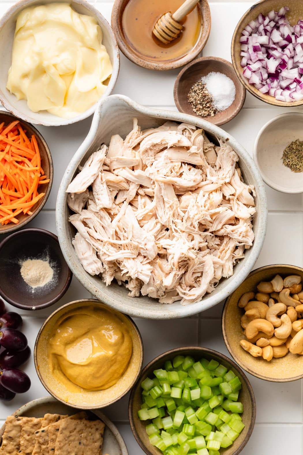 Overhead view of a variety of ingredients for Honey Mustard Chicken Salad in different sized bowls.
