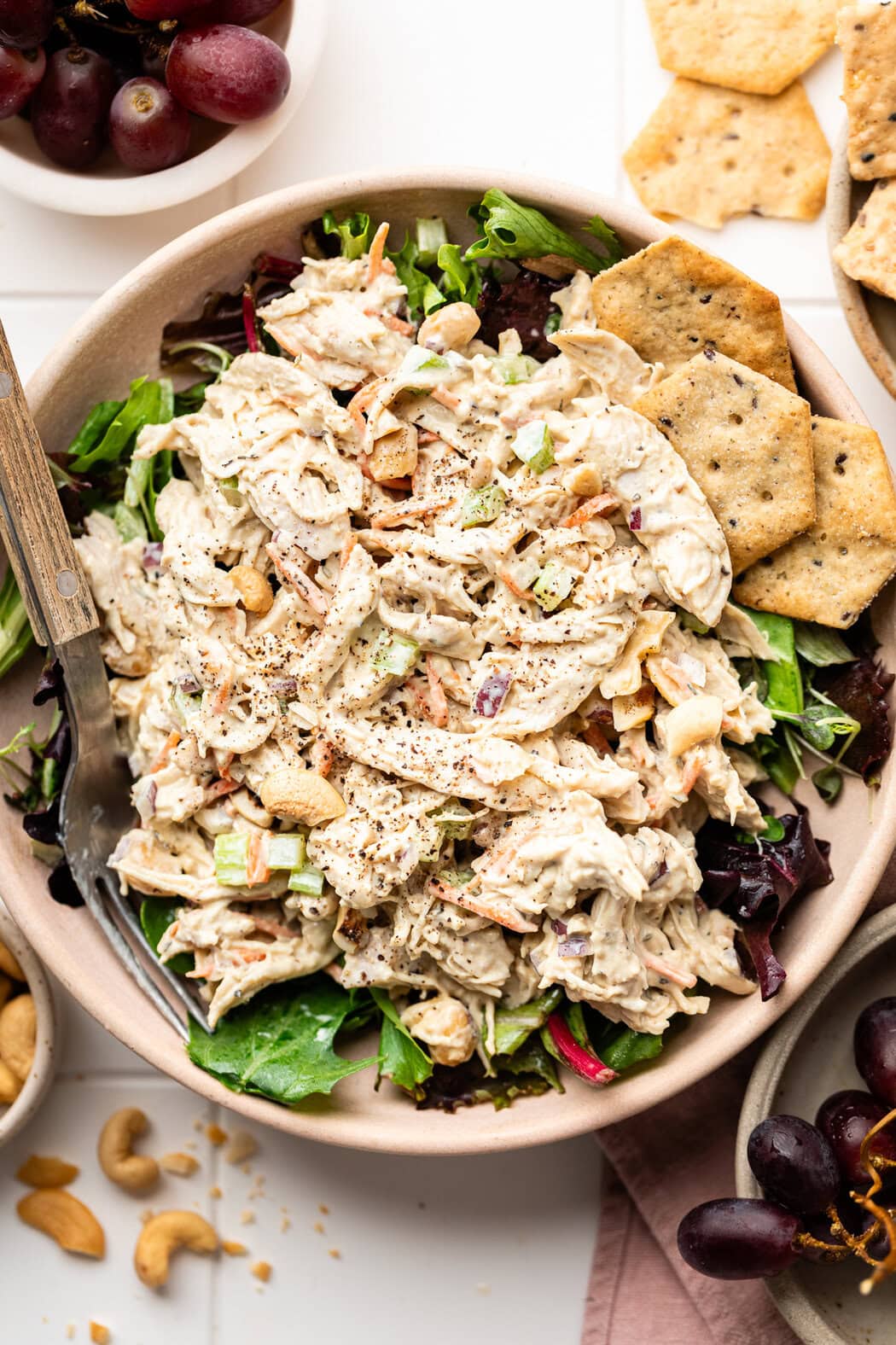 Overhead view of a plate of Honey Mustard Chicken Salad on top of a bed of lettuce and crisp multigrain crackers on the side.