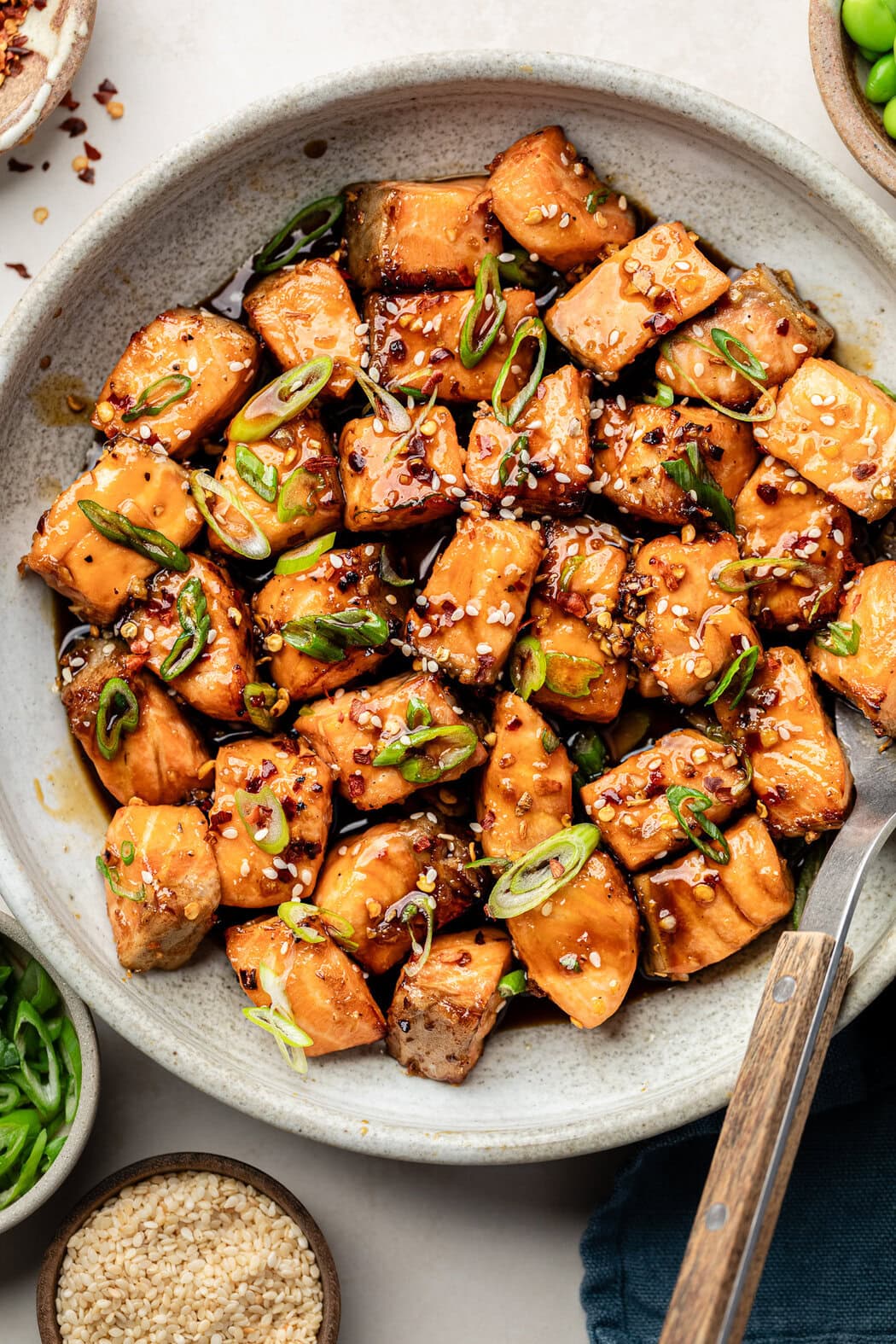 Close up view of a white bowl of Air Fryer Salmon Bites topped with sesame seeds and green onions.
