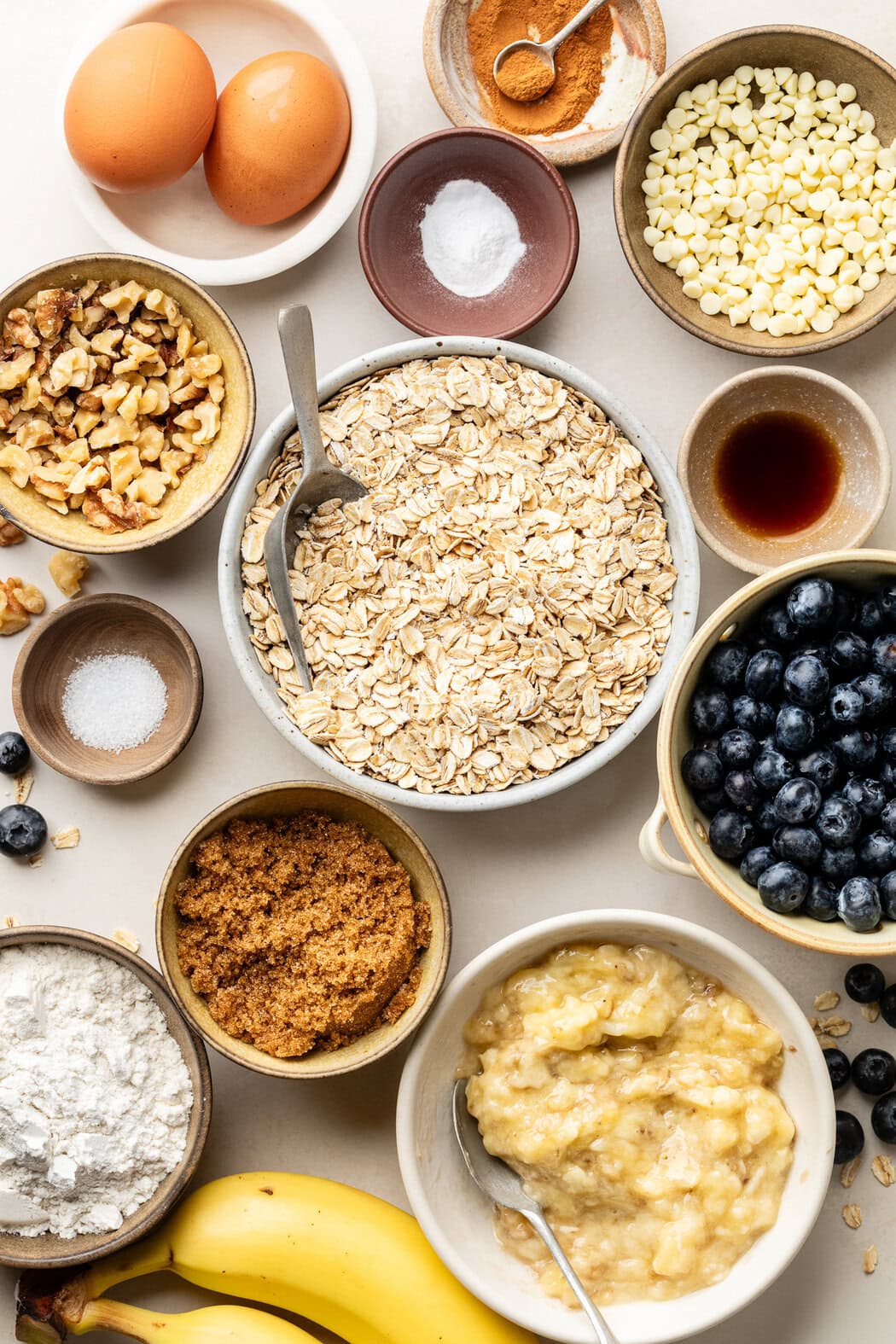 Overhead view of a variety of ingredients for Blueberry Oatmeal Breakfast Cookies in different sized bowls. 