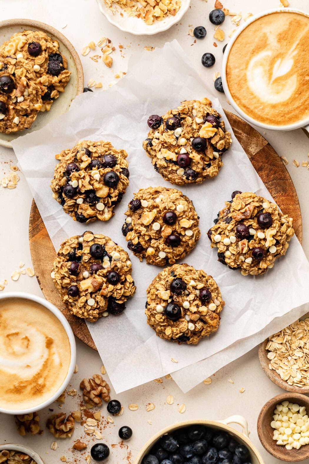 Overhead view of Blueberry Oatmeal Breakfast Cookies on parchment paper next to a frothy latte.