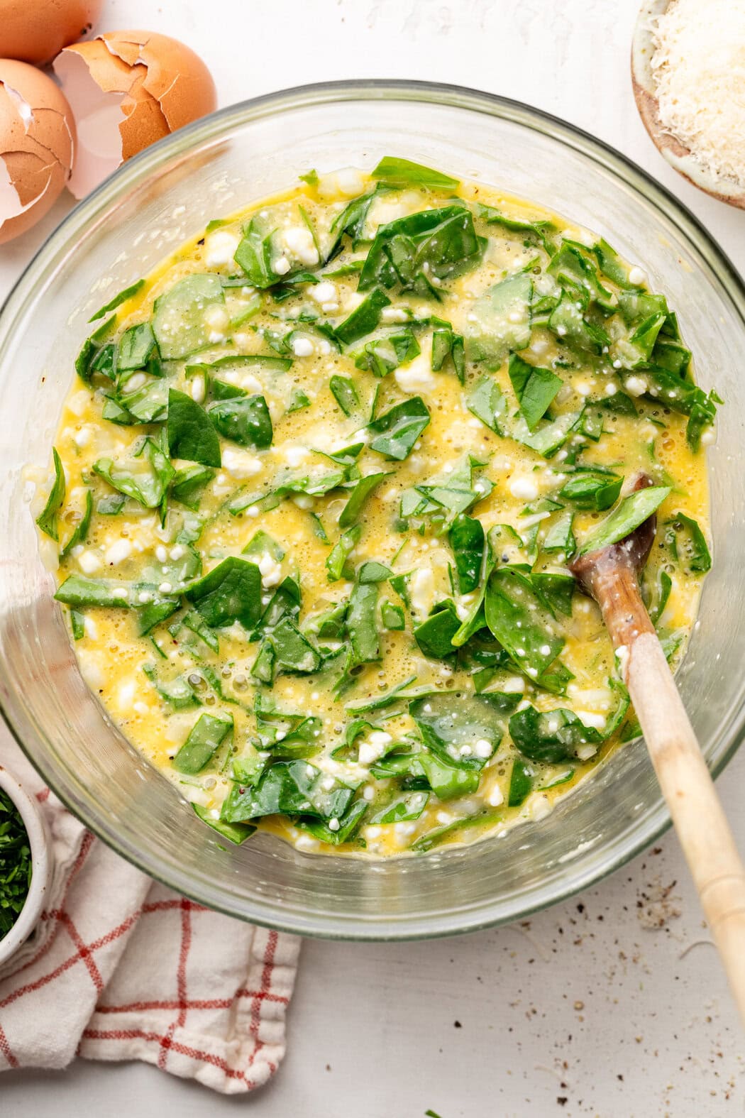 Overhead view of a glass bowl of Cottage Cheese Egg Bake ingredients ready for a baking dish.