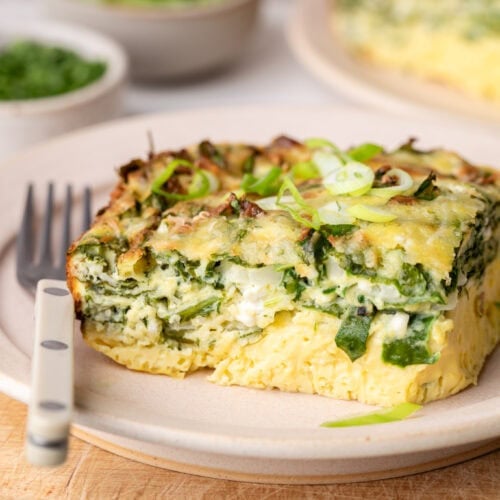 Close up view of a piece of Cottage Cheese Egg Bake on a white plate with a fork on the side.