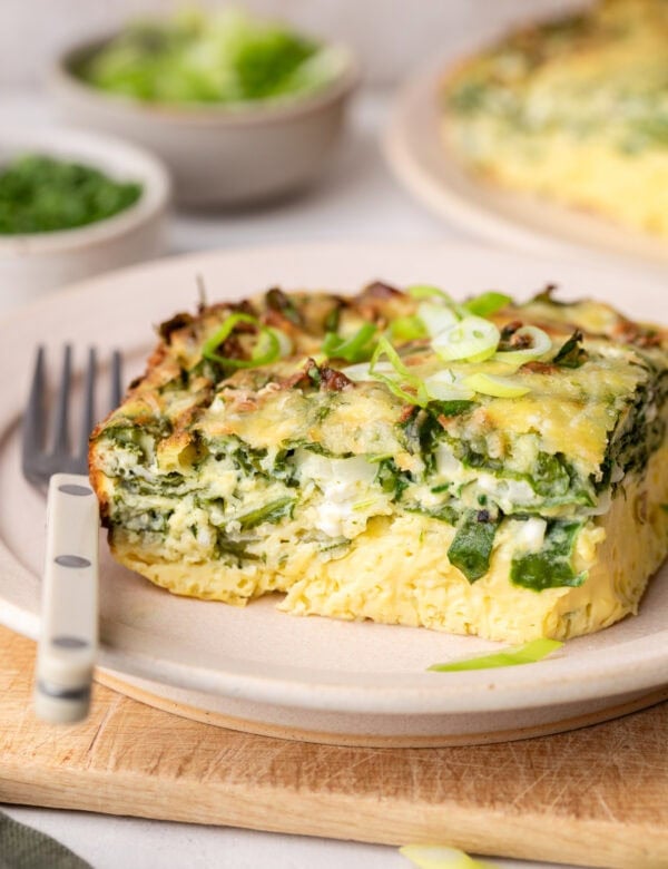 Close up view of a piece of Cottage Cheese Egg Bake on a white plate with a fork on the side.