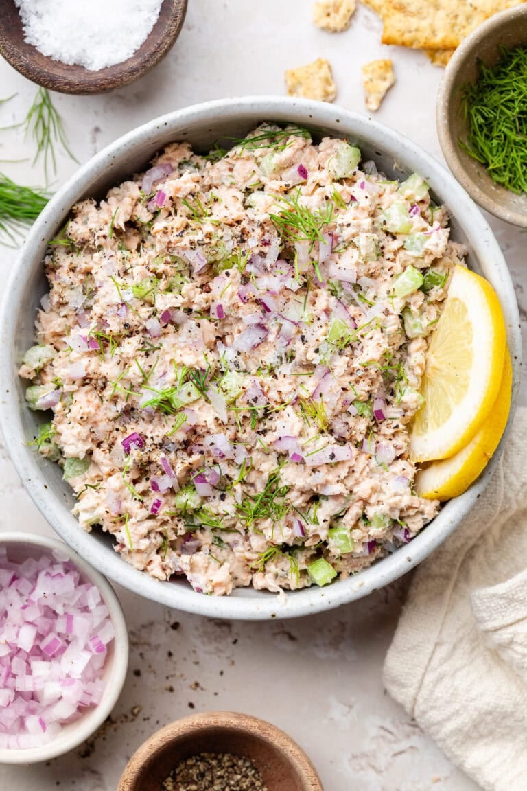 Overhead view of a bowl of My Easy 5-Minute Salmon Salad topped with fresh dill and garnished with lemon wedges.