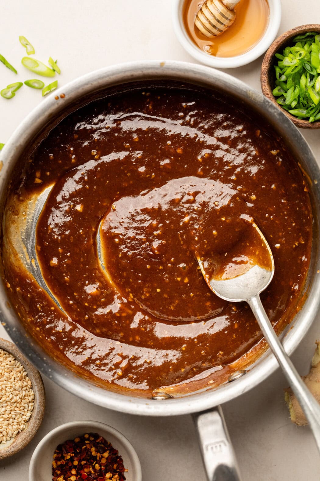 Overhead view of a metal spoon stirring a bowl of Korean BBQ sauce showing a thick consistency