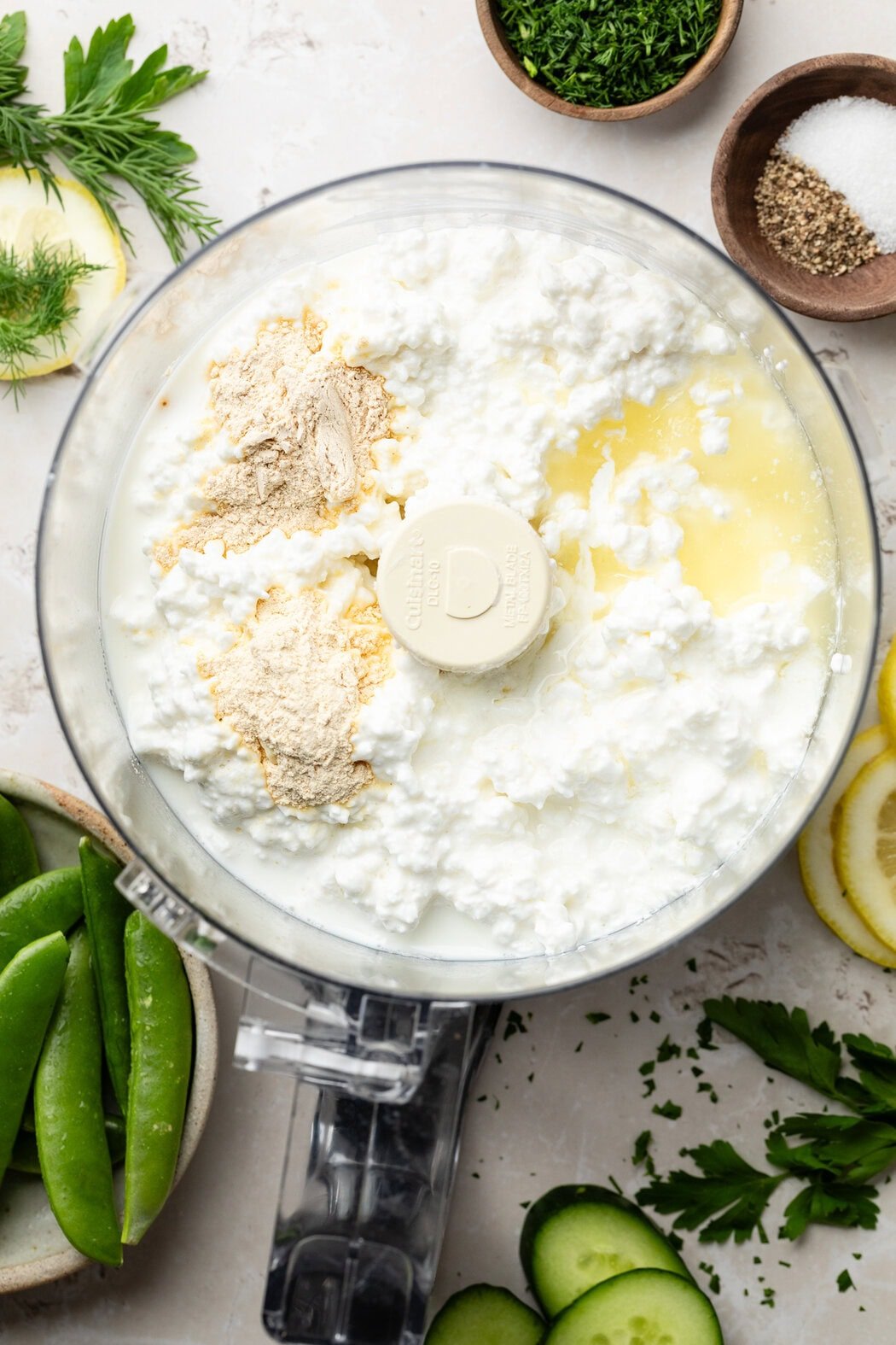 Overhead view of a food processor filled with ingredients for whipped cottage cheese dip ready for blending. 