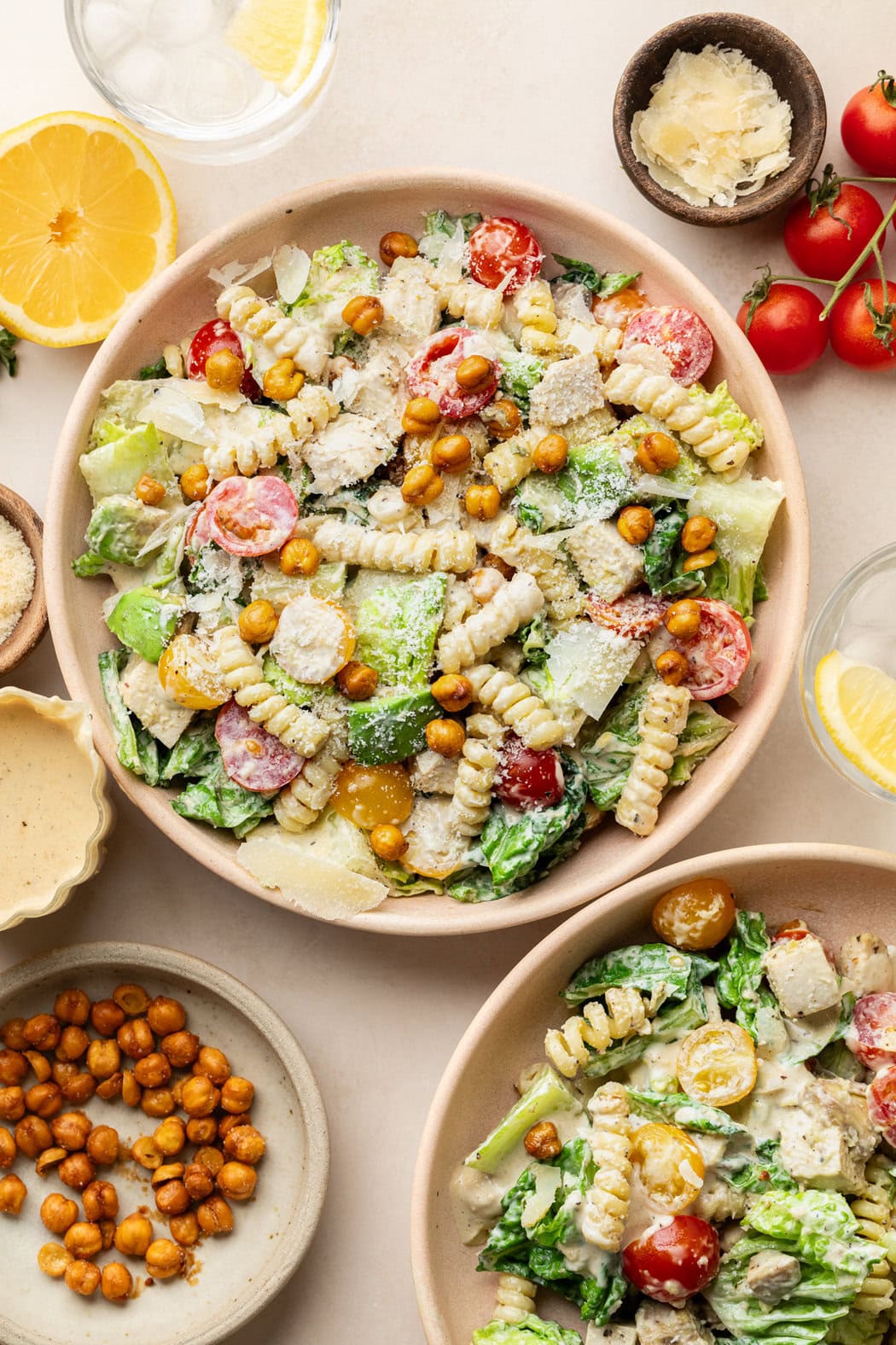 Close up view of two bowls of Chicken Caesar Pasta Salad topped with grated parmesan cheese and roasted chickpeas. 