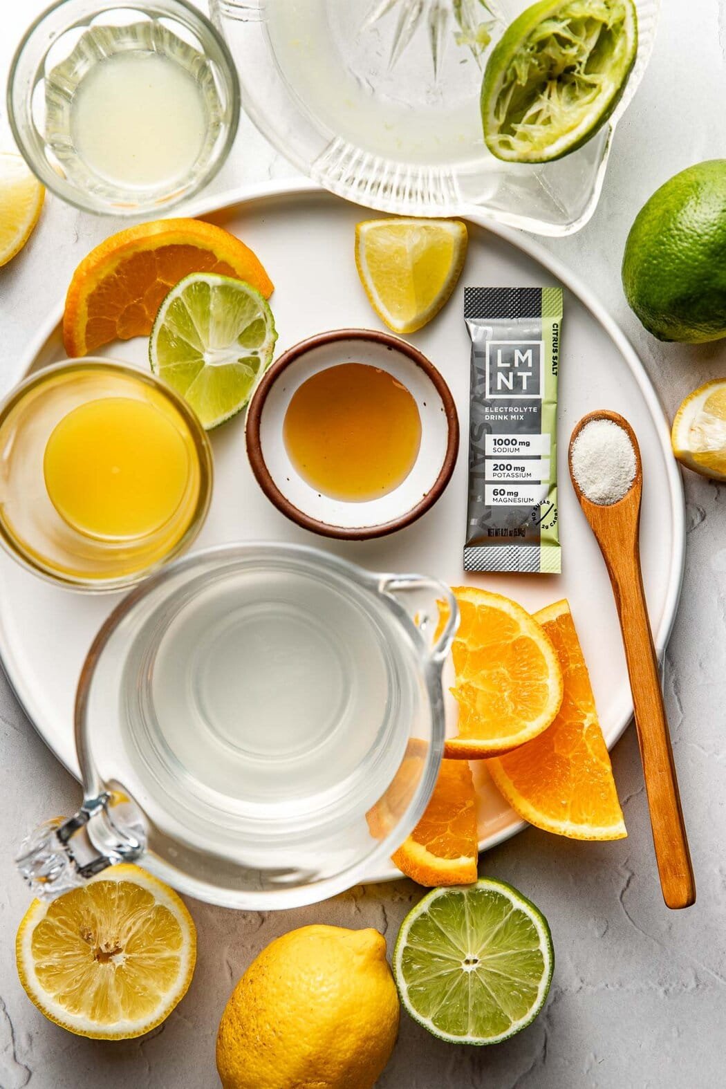 Overhead view of a variety of ingredients for Homemade Gatorade in different sized bowls including fresh fruit and juice.