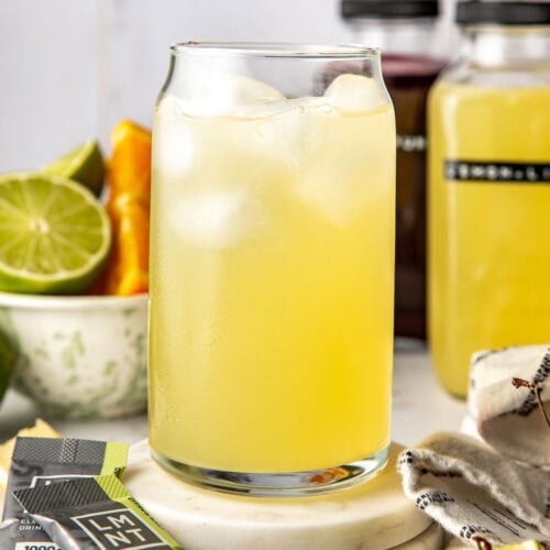 Close up view of a glass of Homemade Gatorade on ice surrounded by fresh fruit.