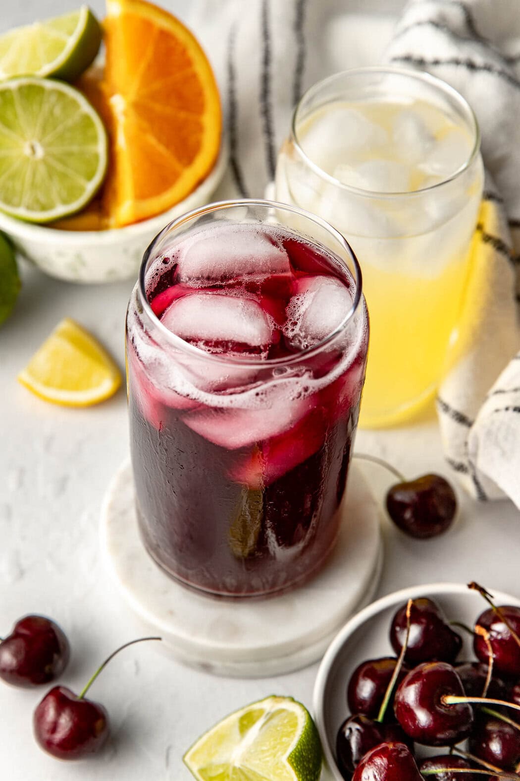 Overhead view of two glasses of colorful Homemade Gatorade on ice with fresh fruit in the background. 