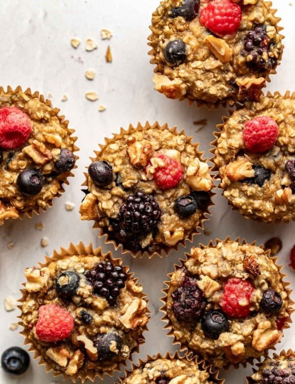 Overhead view mixed berry baked oatmeal muffins on counter topped with fresh berries and walnuts