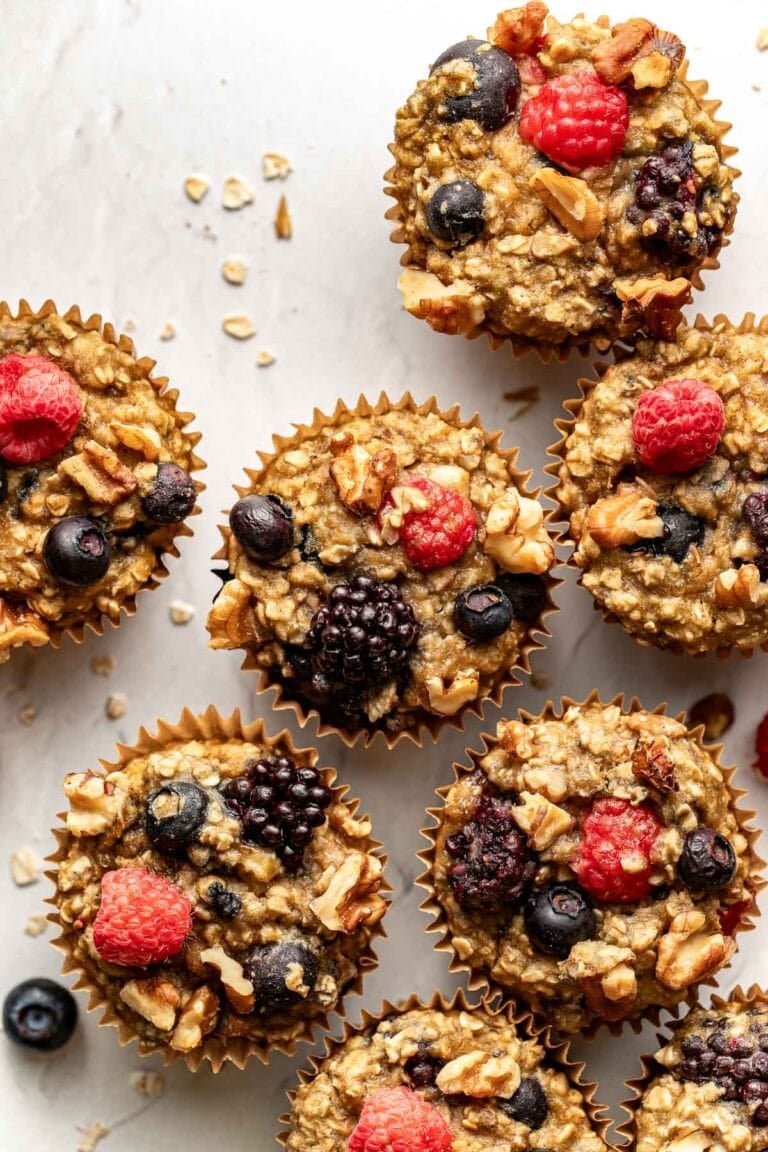 Overhead view mixed berry baked oatmeal muffins on counter topped with fresh berries and walnuts