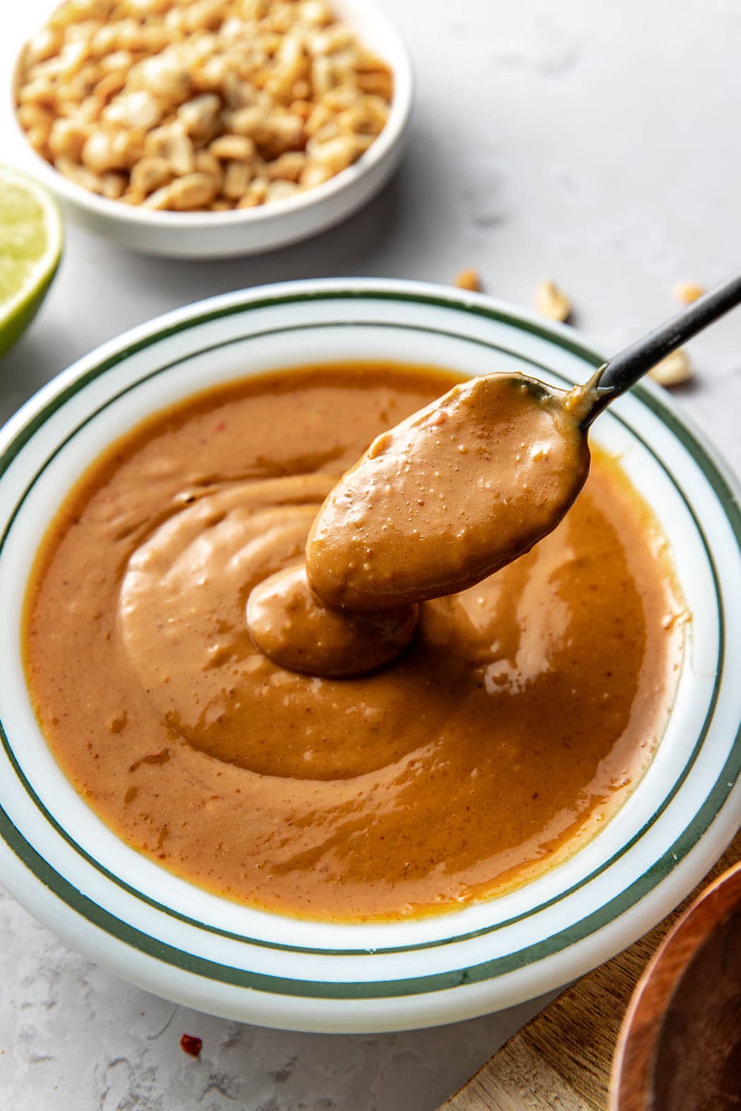 Close up view of a bowl of peanut sauce with a spoon showing a scoop with the texture. 