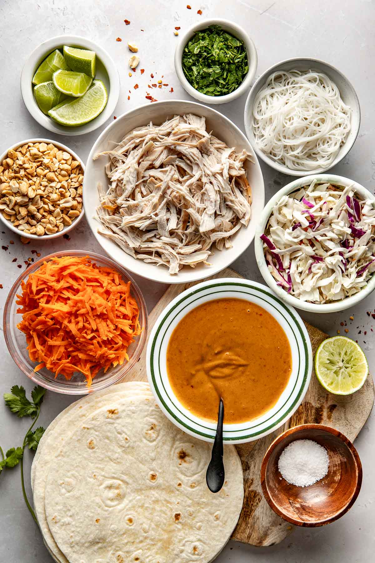 Overhead view of a variety of ingredients for Peanut Chicken Wraps in different sized bowls. 