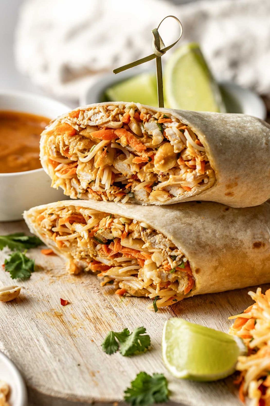 Close up view of two Peanut Chicken Wraps in a tortilla and fresh cilantro on the side. 