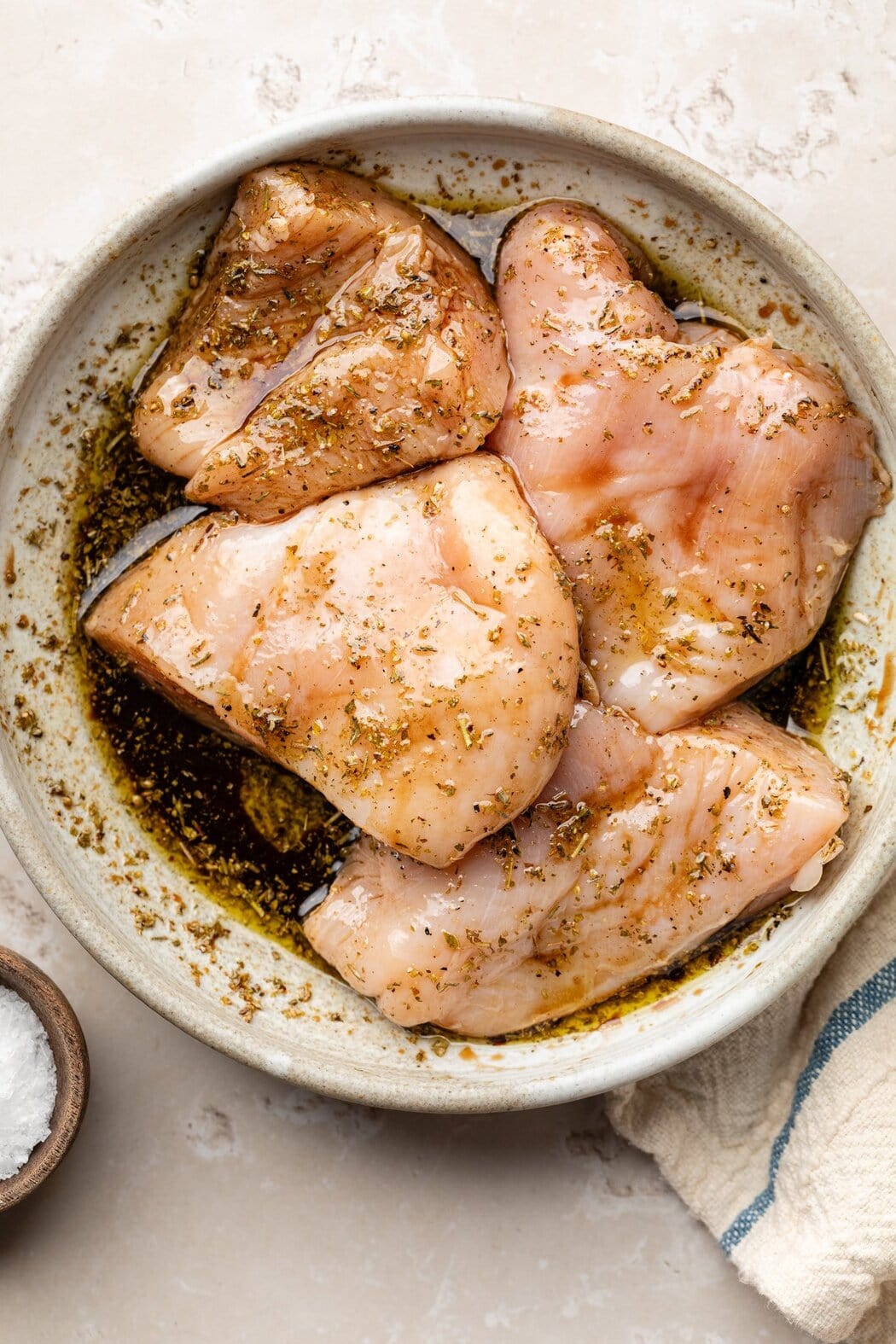 Overhead view of a bowl of chicken breasts marinating in a balsamic reduction.
