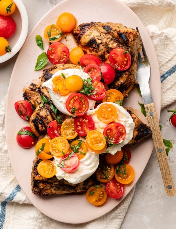 Overhead view platter filled with grilled chicken caprese with melty burrata on top