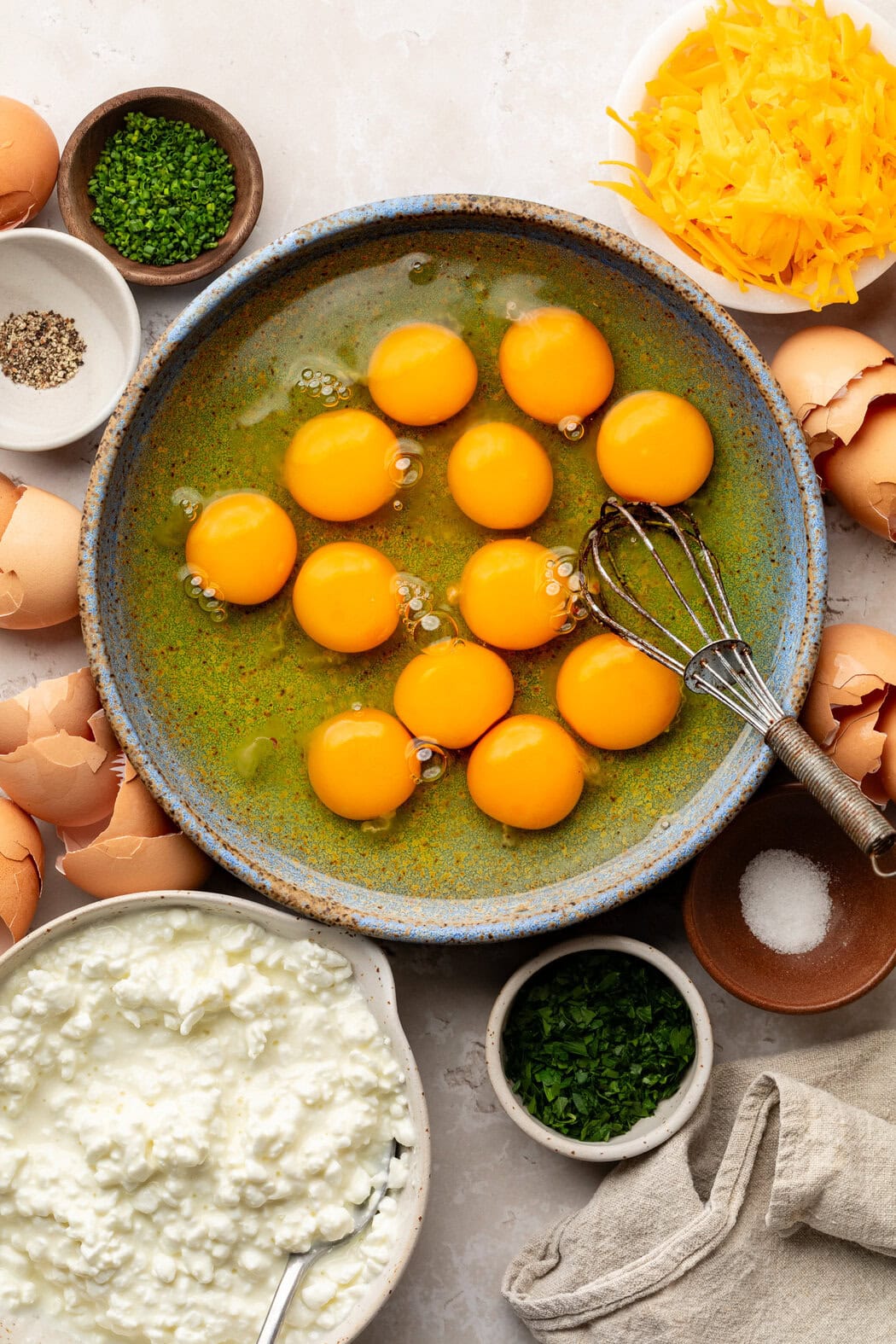 Overhead view of a variety of ingredients for Sheet Pan Eggs with Cottage Cheese in different sized bowls. 