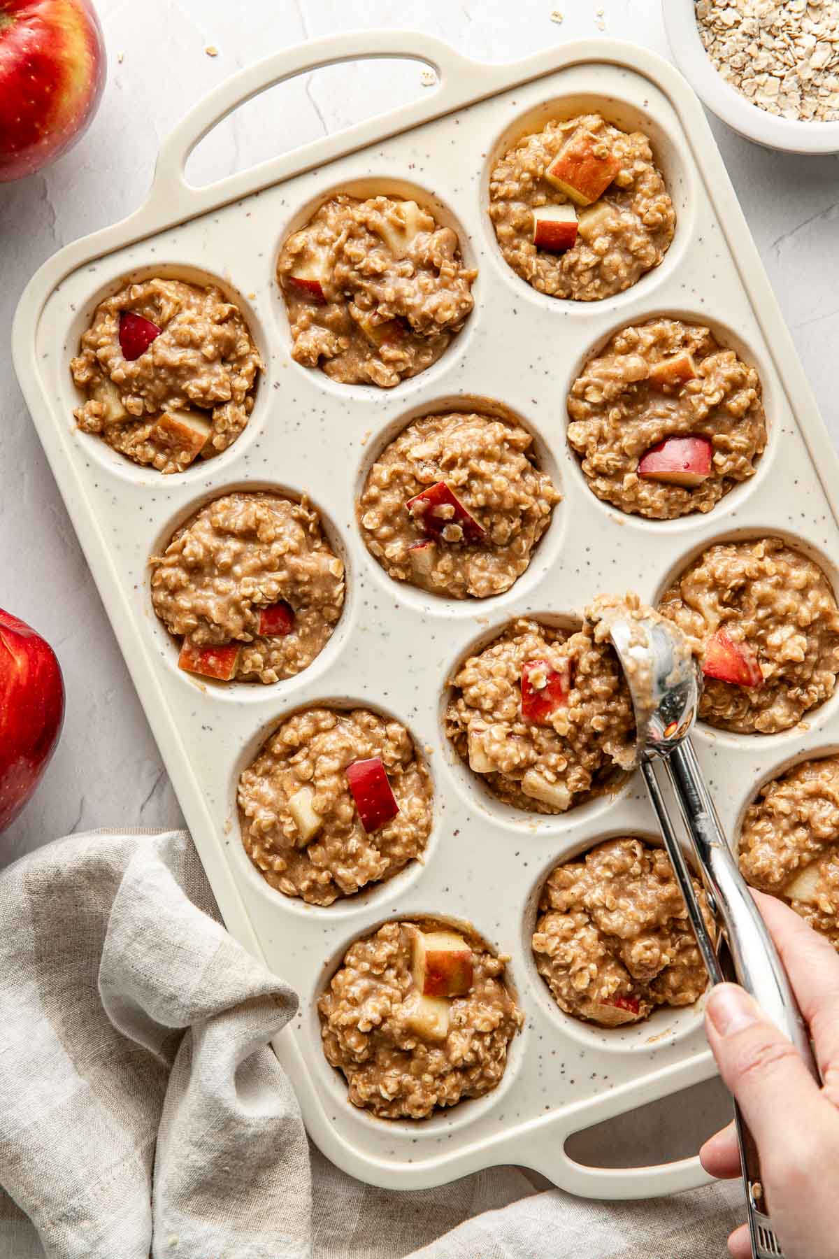 Overhead view of a muffin pan filled with Apple Cinnamon Protein Muffin batter in each well. 