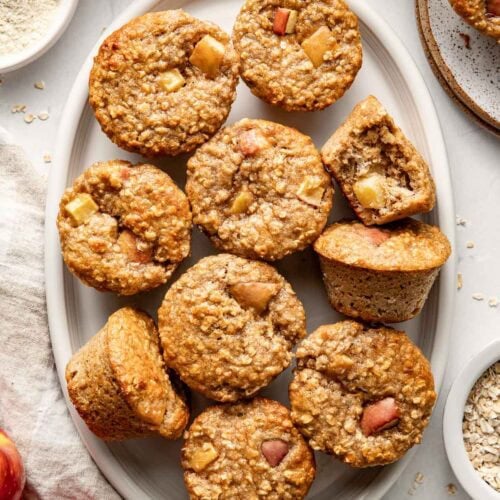 Overhead view of a serving plate of Apple Cinnamon Protein Muffins showing texture and apple pieces in each muffin.