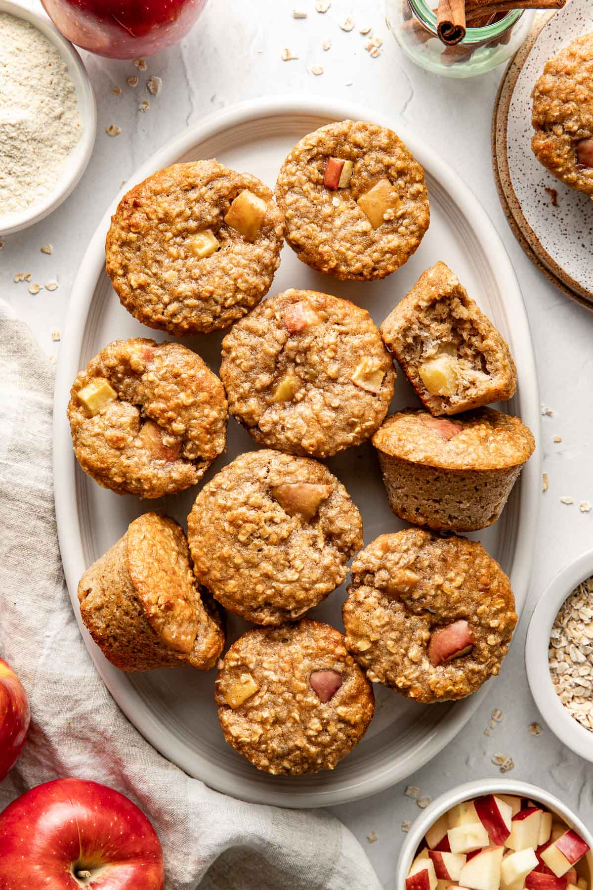 Overhead view of a serving plate filled with Apple Cinnamon Protein Muffins showing texture and apple pieces in each one. 