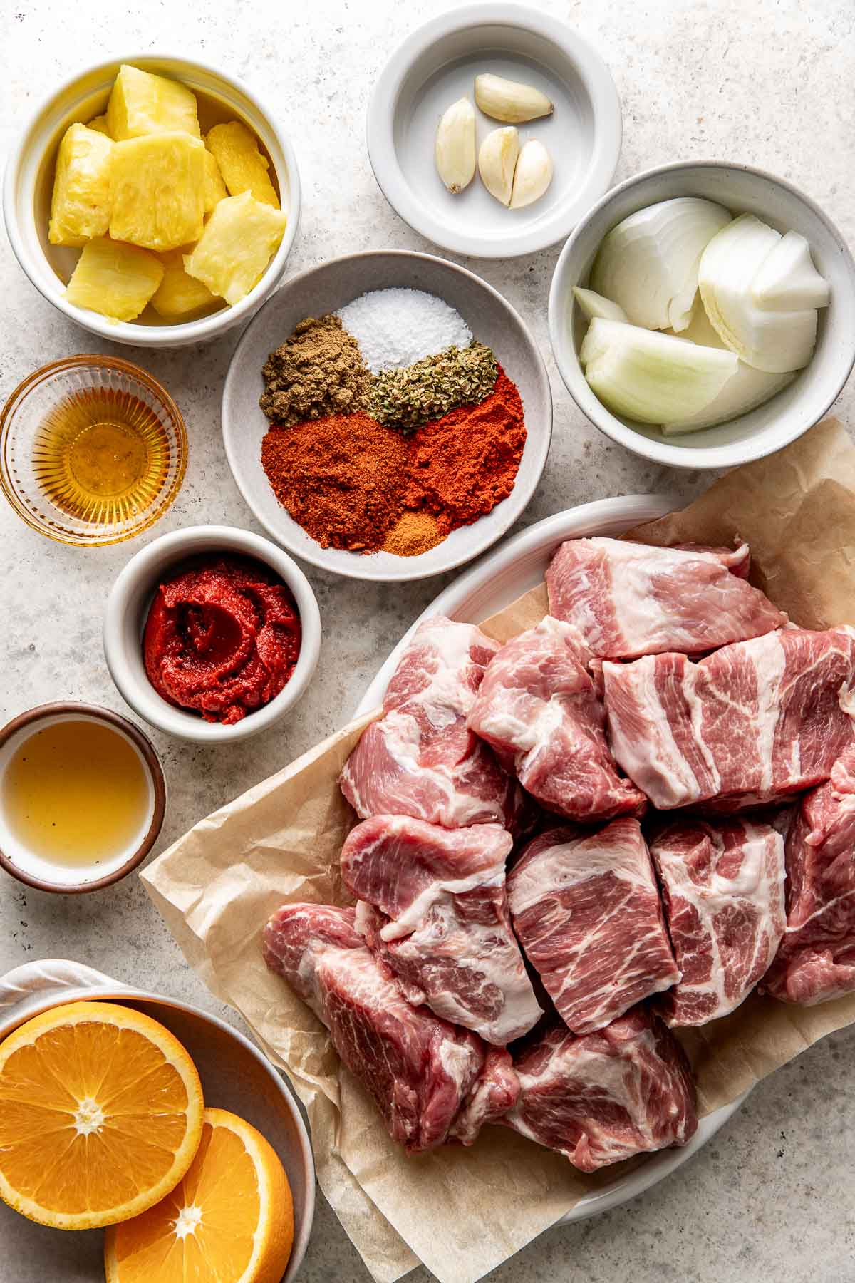 Overhead view of a variety of ingredients for Crockpot Tacos Al Pastor in different sized bowls. 