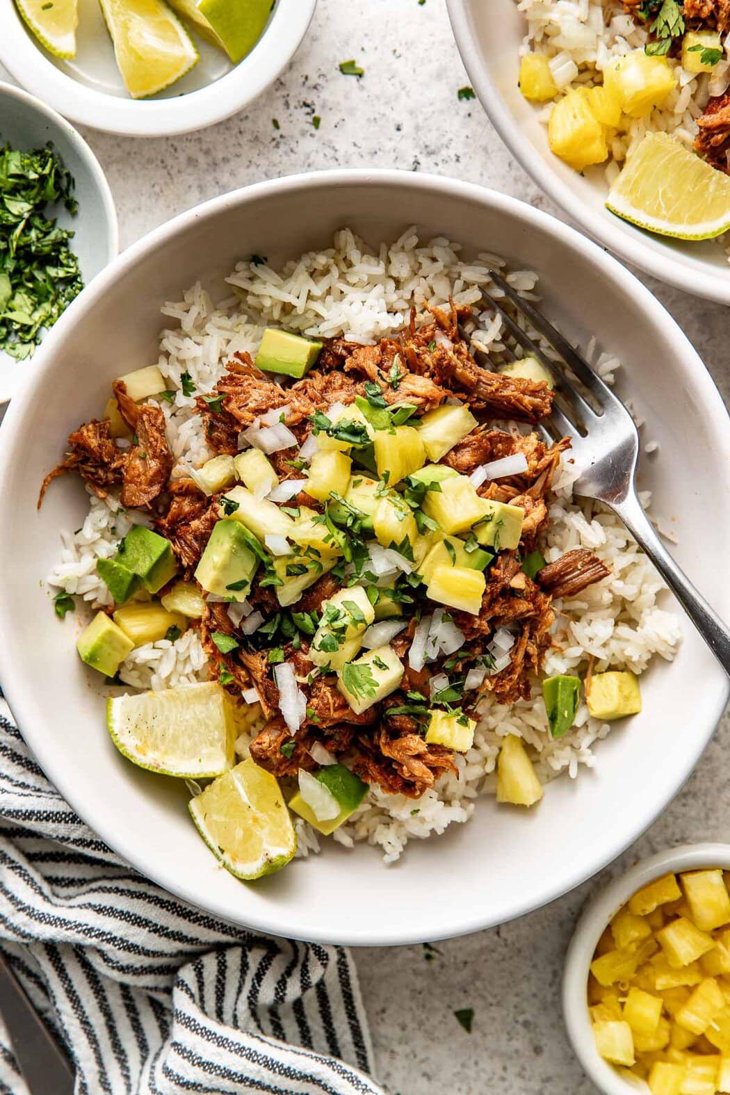 Overhead view of a plate of rice topped with Crockpot Tacos Al Pastor and fresh pineapple and cilantro. 