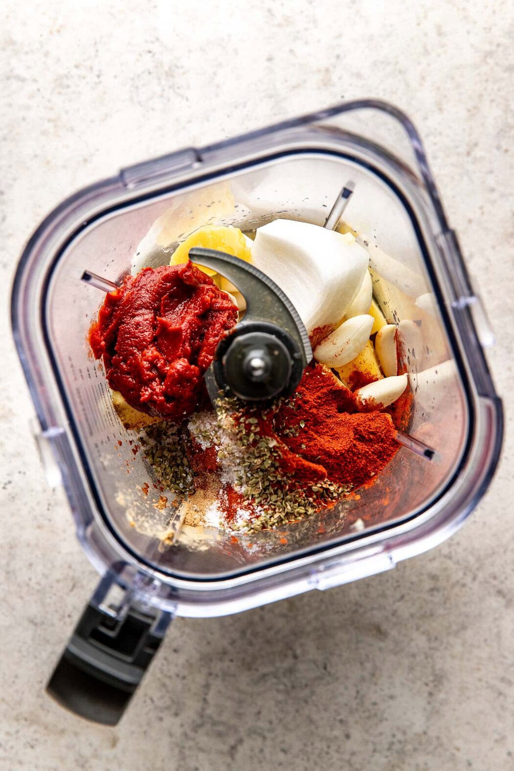 Overhead view of a blender filled with Crockpot Tacos Al Pastor sauce ingredients ready for blending. 