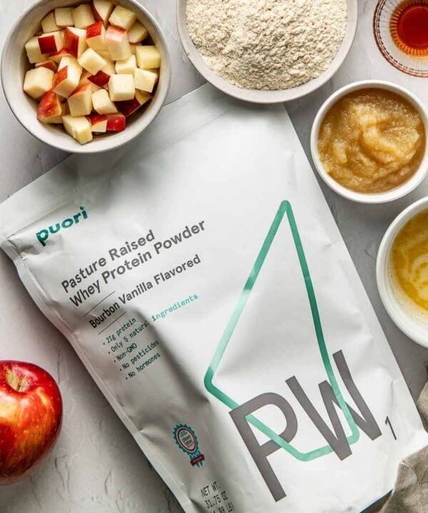 Overhead view of a variety of ingredients for Apple Cinnamon Protein Muffins surrounding a bag of Puori protein powder.