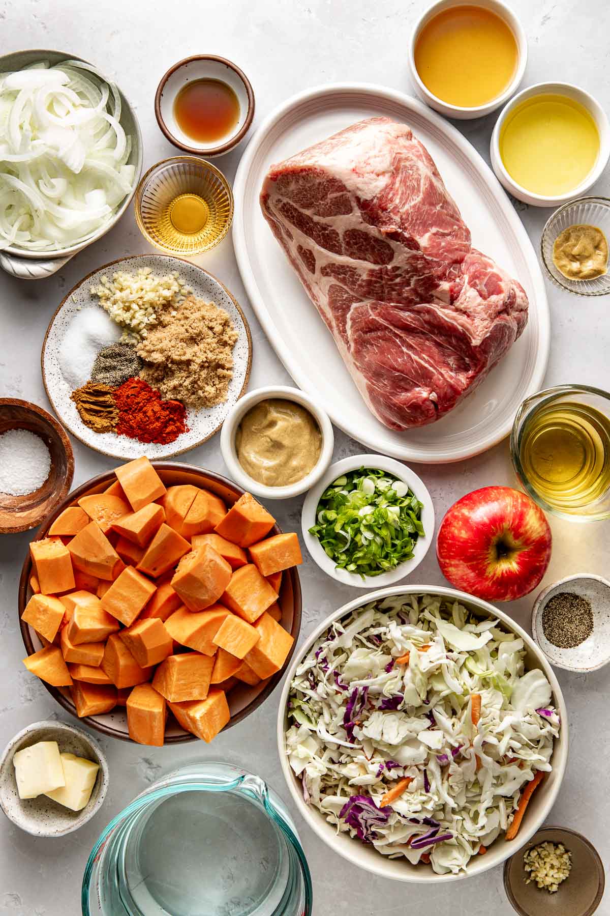Overhead view of a variety of ingredients for Crockpot Apple Cider Pork Bowls in different sized bowls. 