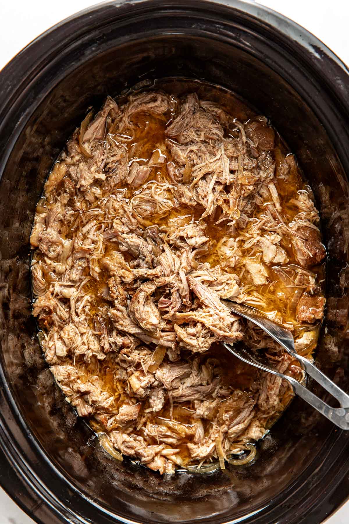 Overhead view of a slow cooker filled with freshly cooked pulled pork. 