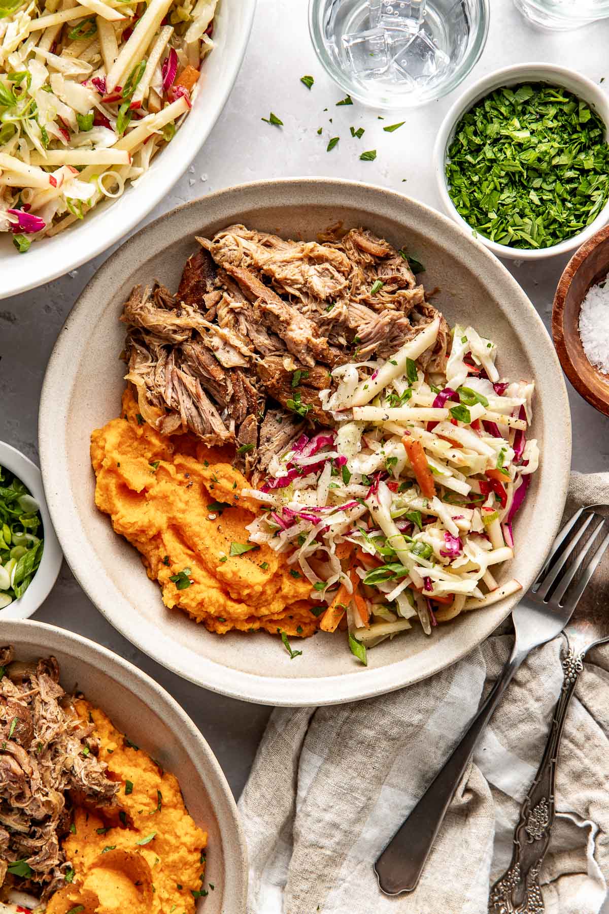 Overhead view of a white plate of Crockpot Apple Cider Pork with mashed sweet potatoes and apple slaw on the side. 