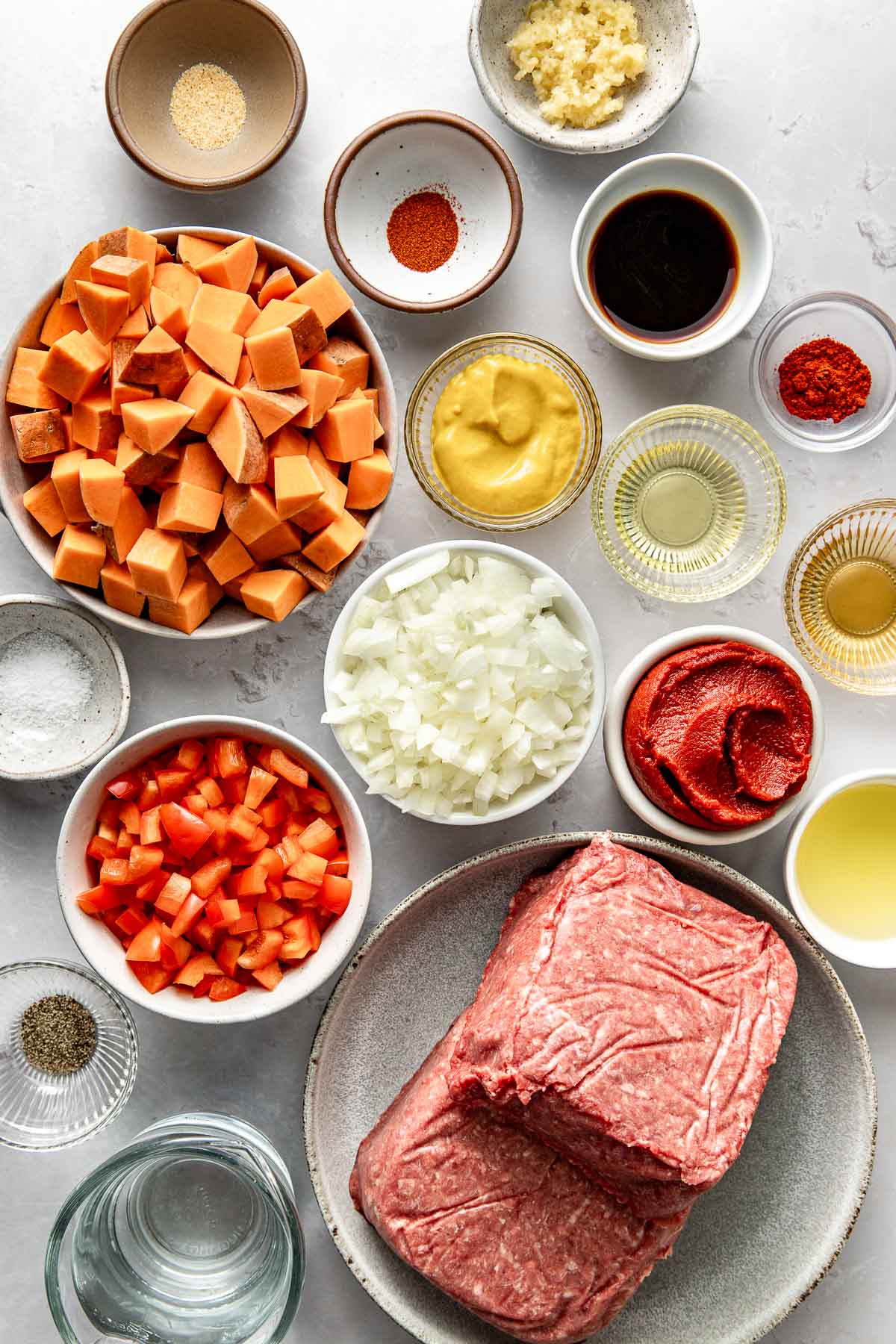 A variety of ingredients for Sloppy Joe Bowls in different sized bowls, including diced sweet potatoes and yellow mustard. 