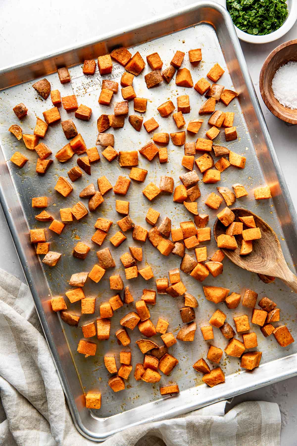 Overhead view of a sheet pan filled with diced sweet potatoes, freshly roasted. 